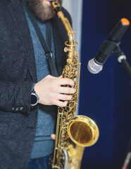 Fototapeta premium Concert view of saxophonist, a saxophone sax player with vocalist and musical band during jazz orchestra show performing music on stage in the scene lights