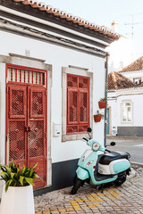 Beautiful blue motorbike and house with typical red doors in Tavira, Algarve, Southern Portugal.