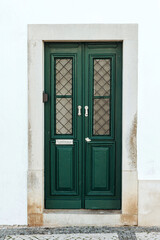 Fototapeta na wymiar Beautiful typical and green door with mailbox in Tavira, Algarve, Southern Portugal.