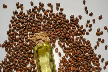Pine nuts oil.shelled pine nuts and a bottle of cedar oil.glass bottle with yellow oil lies in pine...