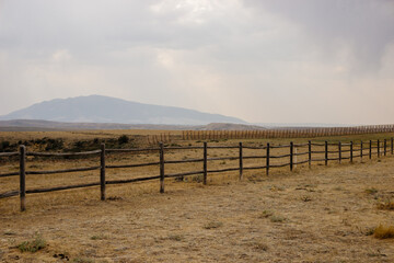 Beautiful mountain landscape on a cloudy autumn day. View of the mountains, wide steppes and a fence in the foreground. Spring panorama with mountains and cloudy sky. Elk Mountain, Wyoming, USA