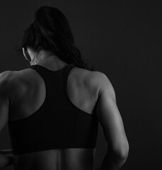 Obraz na płótnie Canvas Sport muscular fitness beautiful female model posing in sport wear bra on dark shadow studio grey background. Black and white 