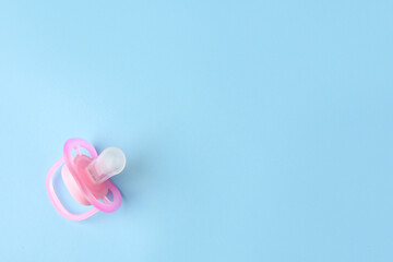 One new baby pacifier on light blue background, top view. Space for text