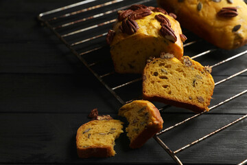 Delicious pumpkin bread with pecan nuts on black wooden table. Space for text