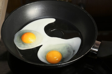 Cooking eggs for breakfast in frying pan on cooktop, closeup