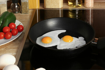 Cooking eggs for breakfast in frying pan on cooktop