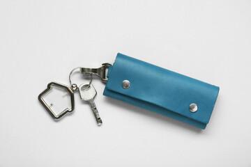 Leather case with key on light grey background, top view