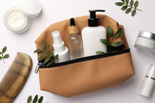 Preparation for spa. Compact toiletry bag with cosmetic products, comb and twigs on white background, top view