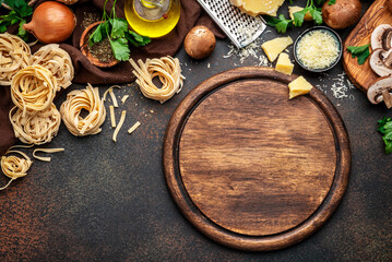 Uncooked pasta, mushrooms, vegetables, cheese and ingredients for tasty cooking on old kitchen table background, top view. Rustic cutting board.  Food banner