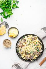 Tagliatelle pasta with mushrooms served on plate with parsley and spices on grey stone kitchen table background, top view. Healthy cooking and eating. Italian food concept