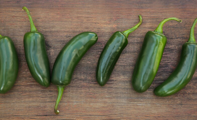 Fresh green jalapeno peppers on wooden table, flat lay