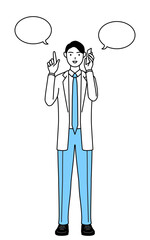 電話をしながら指さしをする白衣を着た男性医師