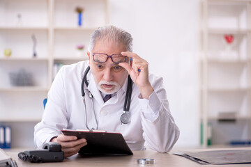 Old male doctor working in the clinic