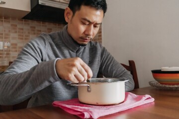 Lonely Asian man having a meal alone in his home.