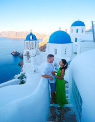 Couple on vacation in Santorini Greece, men and women visit the whitewashed Greek village of Oia during summer vacation - obrazy, fototapety, plakaty