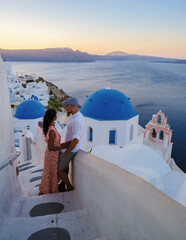 Couple on vacation in Santorini Greece, men and women visit the whitewashed Greek village of Oia...