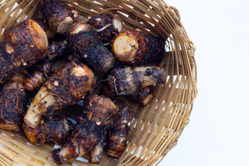 Organic taro fruit in bamboo basket on white background.