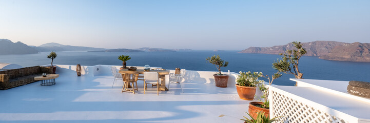 outside terrace of a restaurant by the ocean of Santorini Greece, chairs, and tables with flowers by the ocean.  © Fokke Baarssen
