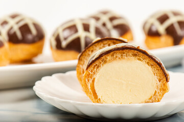 Six pack of gluten-free profiteroles covered in milk and white chocolate and filled with fresh cream