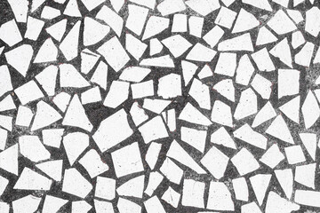 Broken white tile pieces in black concrete pavement texture