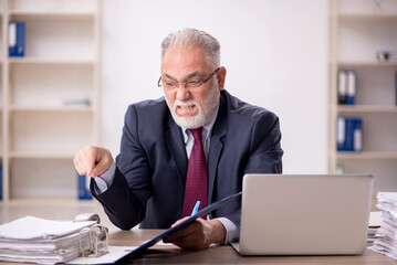 Old male employee sitting at workplace