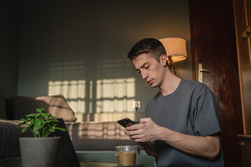 A young guys is using a mobile phone to talk about business at his home