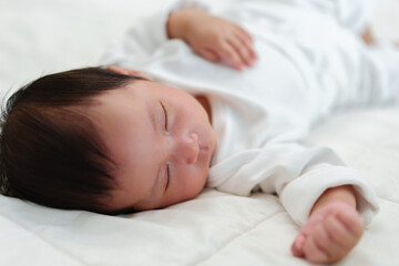 newborn baby sleeping on bed