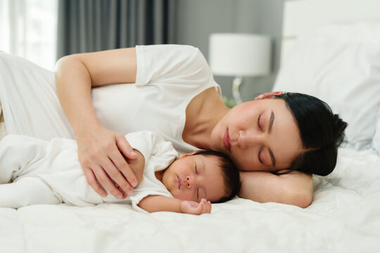 mother and her baby sleeping together on bed