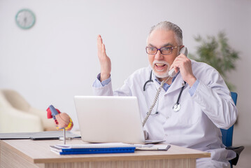 Old male doctor in telemedicine concept