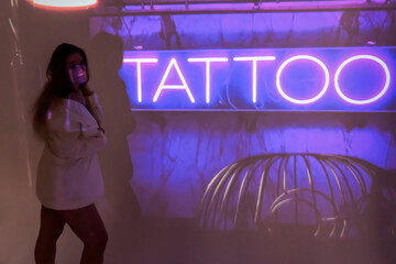 silhouette of a young beautiful woman on the background of neon projector inscriptions, slight blur