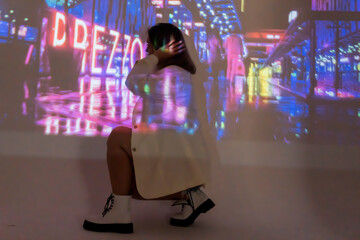 silhouette of a young beautiful woman on the background of neon projector inscriptions, slight blur