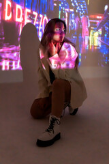silhouette of a young beautiful woman on the background of neon projector inscriptions, slight blur