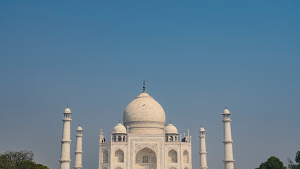 Beautiful ancient white marble Taj Mahal against the blue sky. Symmetrical mausoleum with domes, minarets, arches. India. Agra. Copy Space