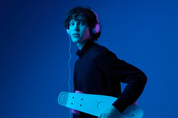 Male teenager in headphones listening to music with skateboard in hand, hipster lifestyle, portrait...