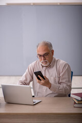 Old male teacher in front of whiteboard