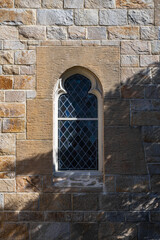 Fototapeta na wymiar window in the stone wall of the church with shadow of trees