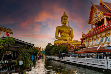 Big Buddha statue at Wat Paknam Phazi Charoen, viewed from the canal at sunset