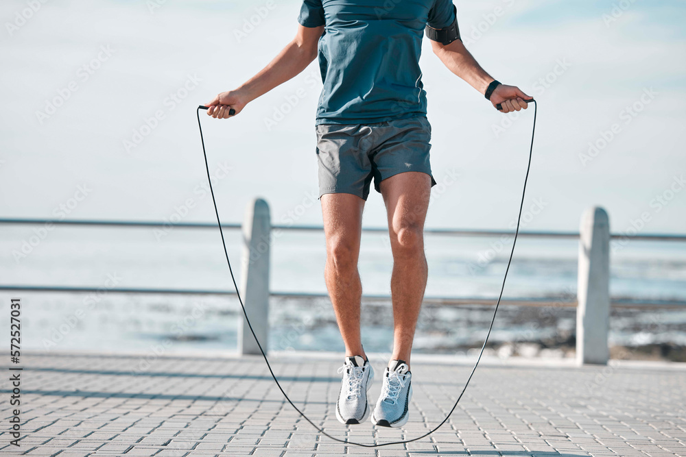 Poster Jump rope, fitness and man by a sea promenade with training, sports and exercise equipment. Health, jumping and body wellness of a athlete doing cardio jump for active lifestyle by the ocean