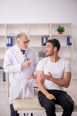 Fototapeta premium Young male patient visiting old male doctor