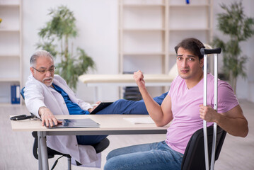Obraz premium Young leg injured patient visiting old male doctor radiologist
