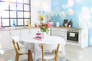Easter eggs and vase with tulips on dining table in kitchen interior