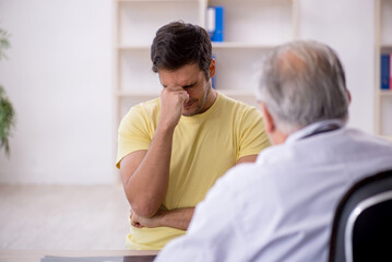 Fototapeta premium Young male patient visiting old male doctor