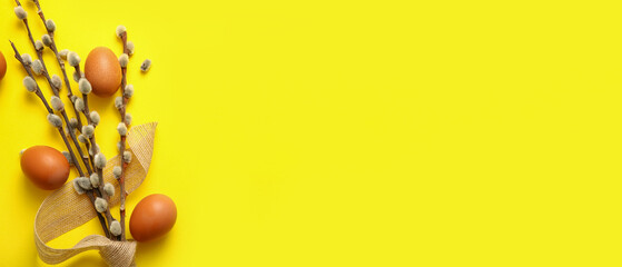Pussy willow branches and eggs on yellow background with space for text