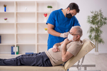 Obraz premium Old male patient visiting young male doctor in vaccination conce