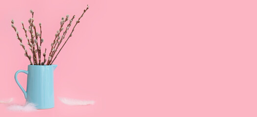 Jug with pussy willow branches and feathers on pink background with space for text