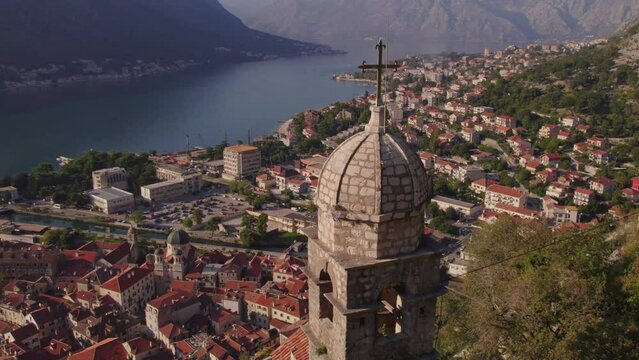Bell tower of Church of Our Lady Remedy with holy cross, Kotor in background