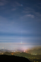 Clouds moving in the sky at night. Neon lights shine on the vibrant cityscape. Hazy and dreamy city night view. Lion's Head Mountain, New Taipei City, Taiwan