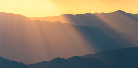 Fototapeta na wymiar Panoramic scene of sunlight shining through the mountain range at sunset.