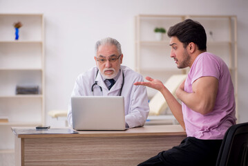 Fototapeta premium Young male patient visiting old male doctor