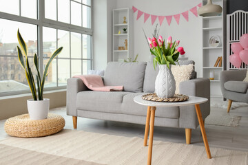 Interior of living room decorated for Easter celebration with tulips in vase and sofa